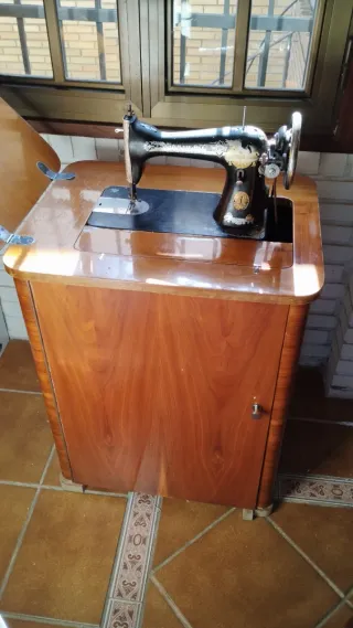 Máquina de coser antigua con mueble de madera.