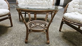 Sofá y sillones de mimbre con mesa de cristal