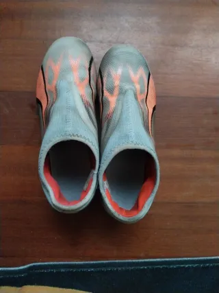 Botas de fútbol niño grises y naranjas marca puma.