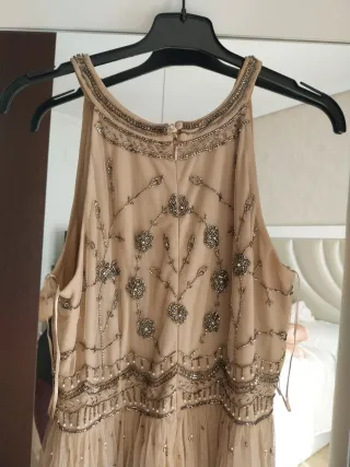 Vestido largo beige y dorado con pedrería.