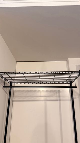 Perchero metálico industrial con ruedas y baldas.