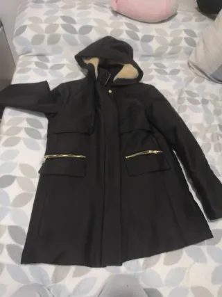Abrigo negro con capucha y cremalleras doradas
