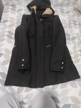 Abrigo negro con capucha y cremalleras doradas