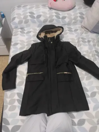 Abrigo negro con capucha y cremalleras doradas