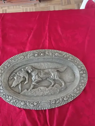 Peça decorativa antiga em metal com cena de caça