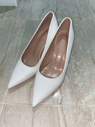 Tacones blancos elegantes con tacón dorado