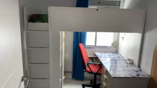 Cama alta con escritorio y armario.