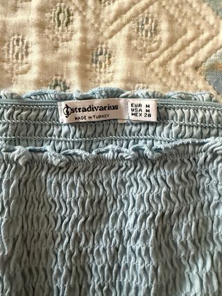 Crop top arrugado azul sin hombros.