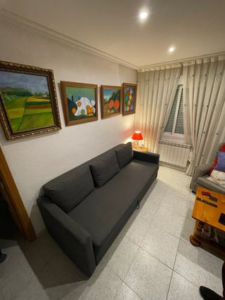 Sofá-cama amplio y cómodo en color gris oscuro.