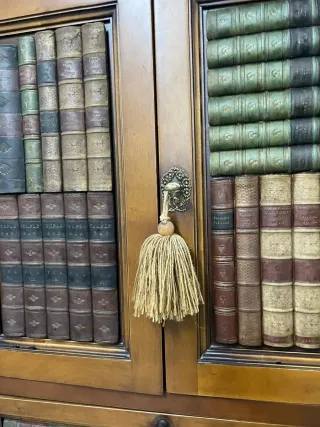 Mueble de madera cerezo con libros decorativos.