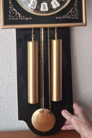 Reloj de pared clásico dorado y negro funcionando