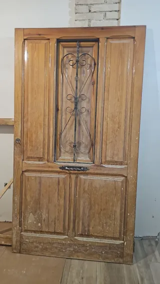 Puerta madera antigua con reja seguridad.