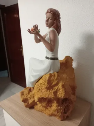 Statuetta natalizia in porcellana di una donna seduta su una pietra