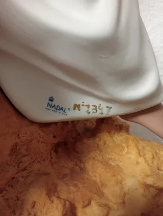 Statuetta natalizia in porcellana di una donna seduta su una pietra