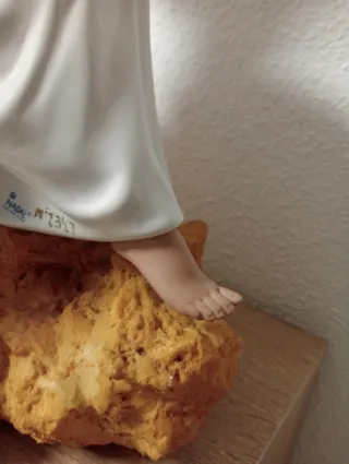 Statuetta natalizia in porcellana di una donna seduta su una pietra