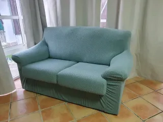 Sofá de tela verde con cojines.