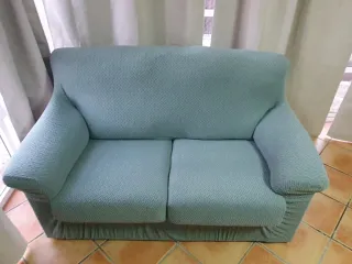 Sofá de tela verde con cojines.