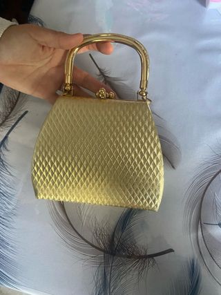 Bolso de mano dorado con asa metálica