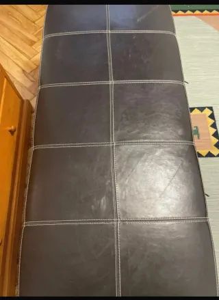 Banco de piel negro con patas de madera.