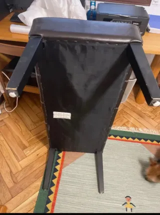 Banco de piel negro con patas de madera.