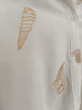 Blusa blanca con bordados conchas.