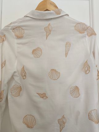 Blusa blanca con bordados conchas.