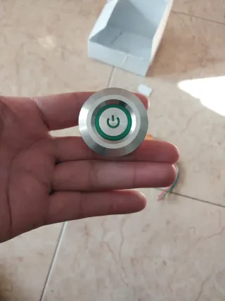 Botón pulsador metálico con símbolo de encendido