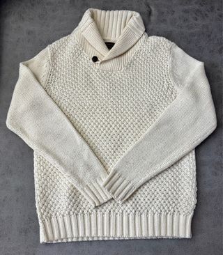 Jersey de punto blanco con cuello de pico y botón.