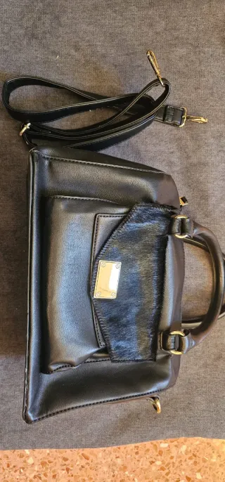 Bolso negro con bolsillo delantero efecto pelo.
