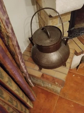 Olla antigua de hierro para calentar agua al fuego