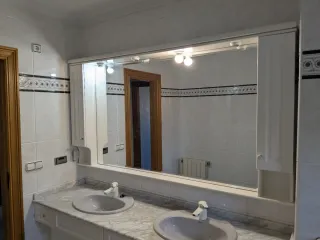 Espejo de baño con mueble y lavabos.