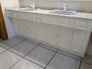 Espejo de baño con mueble y lavabos.