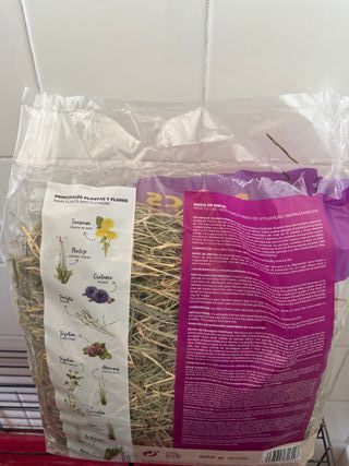 Jaula para conejo con heno, pienso y absorvente.