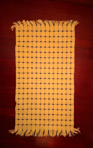 Alfombra tejida amarilla con detalles azules