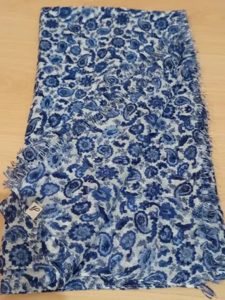 Pañuelo estampado tonos azules, acabado flecos.