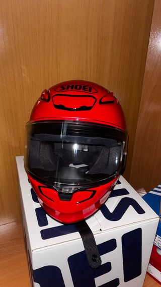 Casco rojo de moto, marca Shoei.