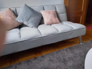 Elegante sofá cama gris con patas decorativas inox