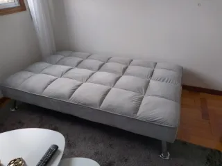 Elegante sofá cama gris con patas decorativas inox