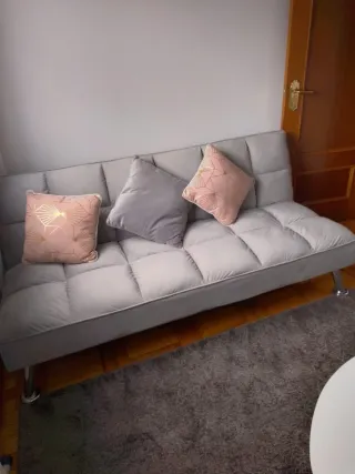 Elegante sofá cama gris con patas decorativas inox