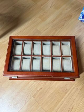 Relojero de madera con tapa de cristal.