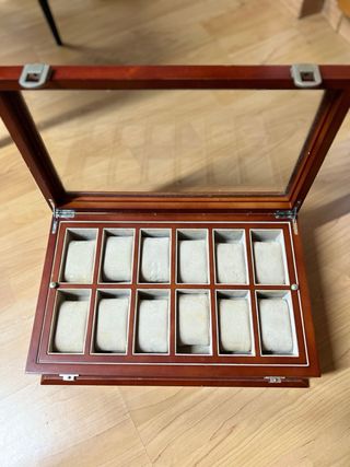 Relojero de madera con tapa de cristal.