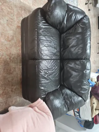 Sofá de piel negro con manta rosa