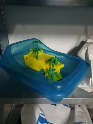 Tortuguera de plástico con palmeras y rampa.