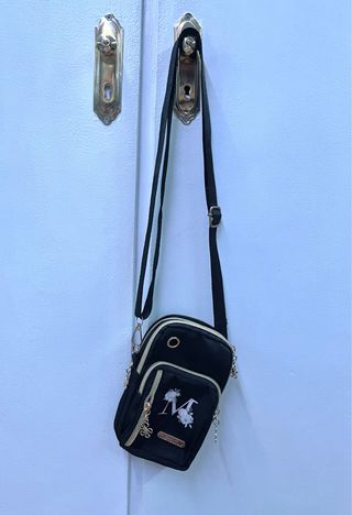 Bolso móvil negro con M y flores.