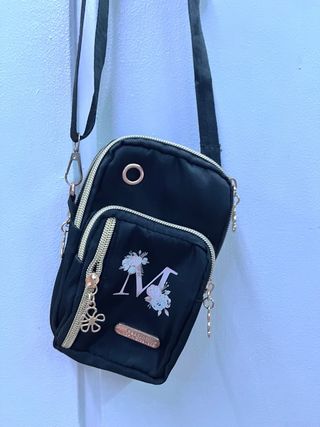 Bolso móvil negro con M y flores.