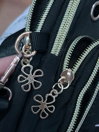 Bolso móvil negro con M y flores.