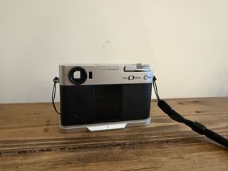 Fotocamera Fujifilm X Half argentata e nera con cinturino