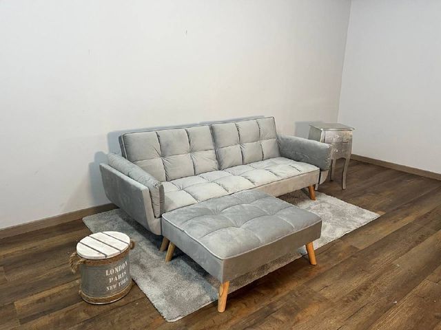 Sofá gris moderno con chaise longue a juego y puff