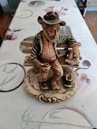 Figura antigua de hombre sentado en banco