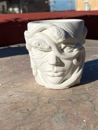 Vasetto in gesso con volto e serpenti